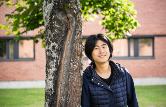 Student standing by a tree