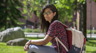 Young woman sitting outside, with backpack on her back.