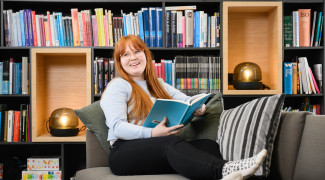 Tyttö istuu sohvalla ja lukee kirjaa